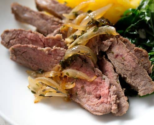 sliced flank steak with cooked onions, spinach and squash in bowl