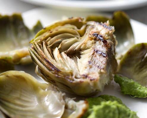 midway through eating an artichoke with green dip