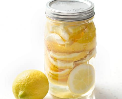 lemon rind in mason jar with vinegar on white background