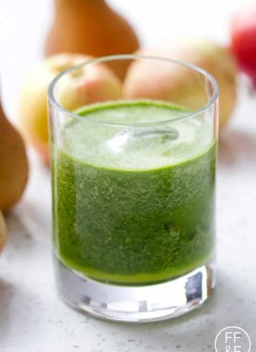 glass of green juice in front of fruit