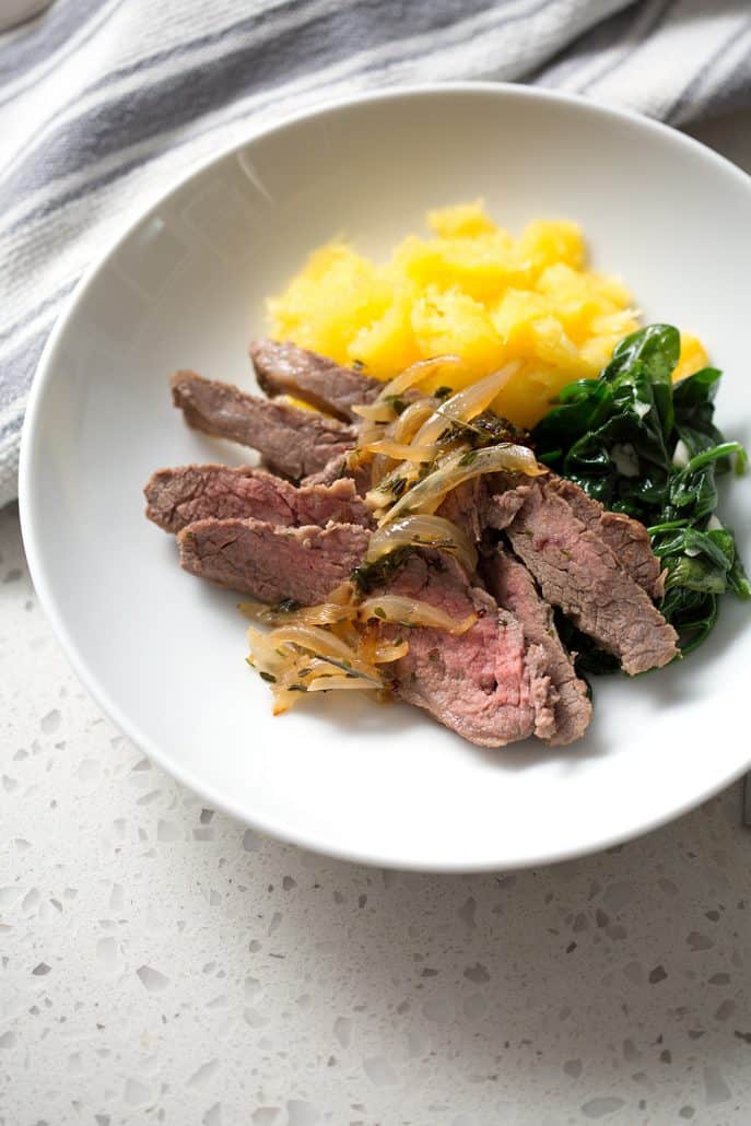 sliced flank steak with cooked onions, spinach and squash in bowl