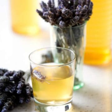 glass and bottle of kombucha tea with bunches of lavender on white background