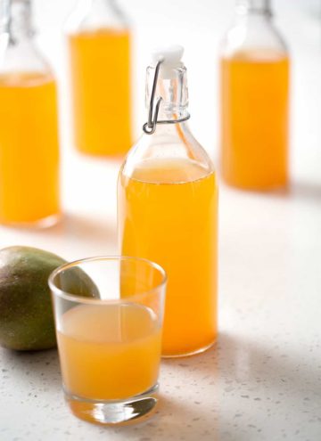 bottle of mango kombucha tea with mango on white background