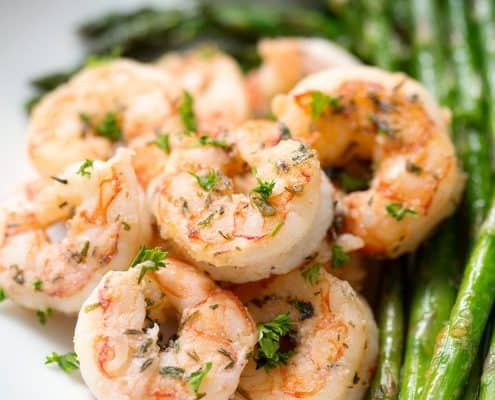 plate of seasoned shrimp with asparagus on white background