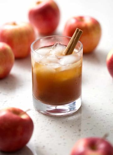 glass of kombucha in glass with apples and cinnamon stick on white background