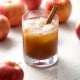 glass of kombucha in glass with apples and cinnamon stick on white background