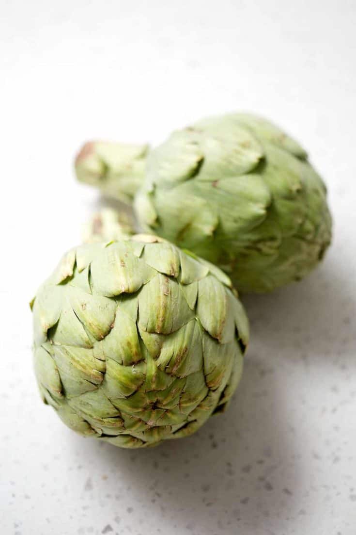 whole fresh artichokes on white background