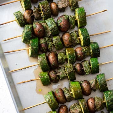 grilled meat skewers with vegetables on baking sheet