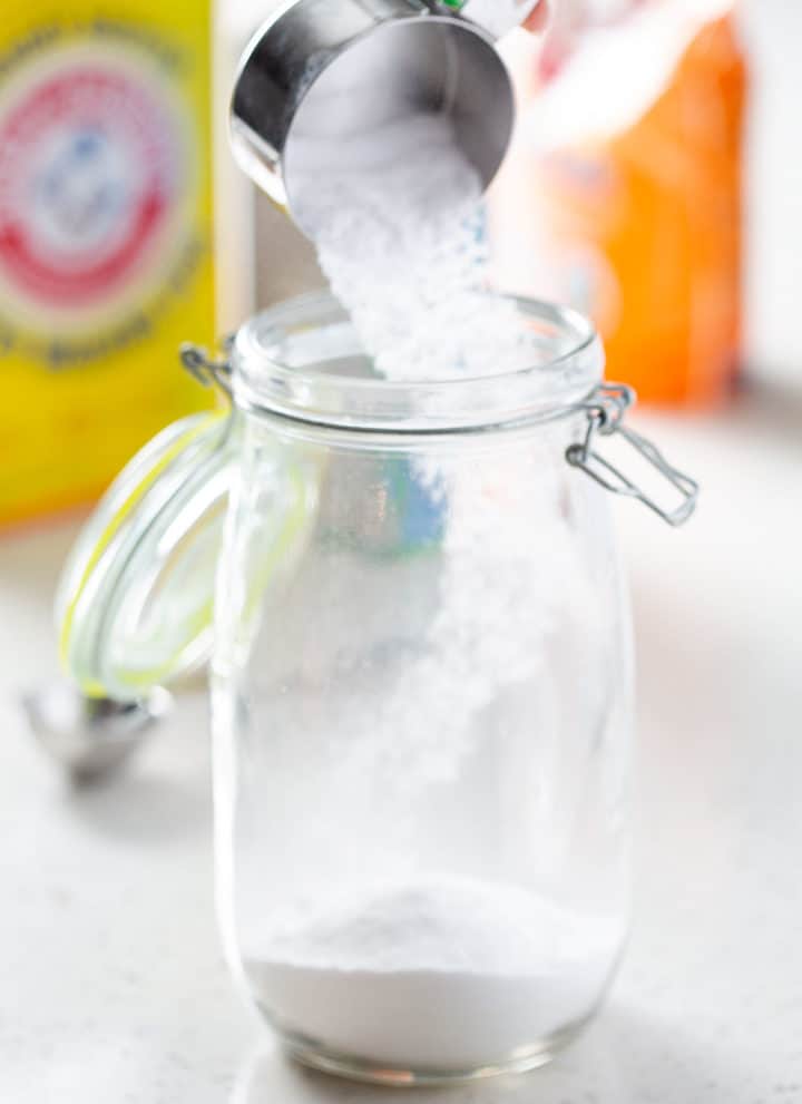 pouring homemade laundry detergent powder into glass container