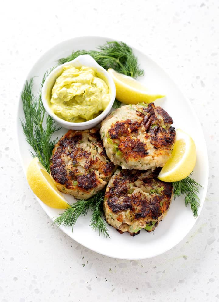 platter of aip salmon cakes surrounded by lemon slices, fresh dill and dip