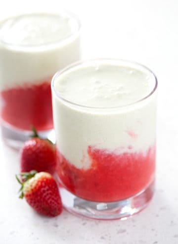 glasses of iced strawberry matcha latte surrounded by fresh strawberries