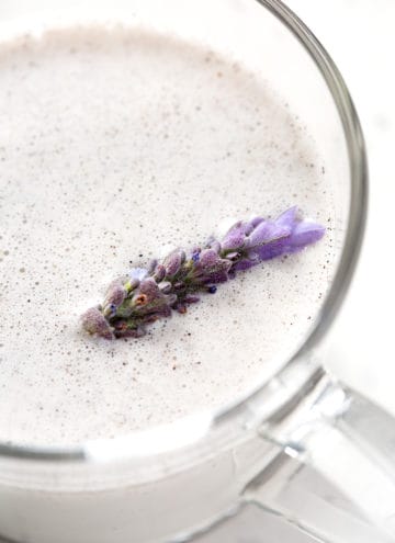close up of cup of lavender milk tea with fresh lavender floating