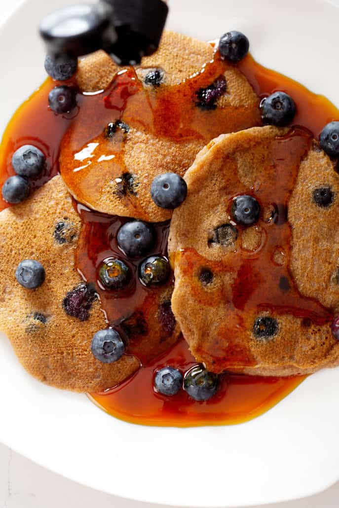 pouring maple syrup on AIP Blueberry Pancakes from above